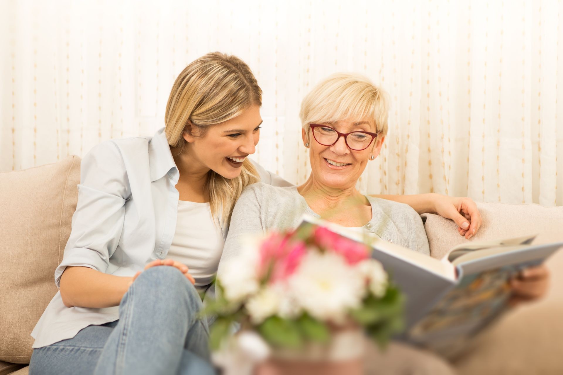 Mother and daughter watch a family photo album, remembering beautiful moments.